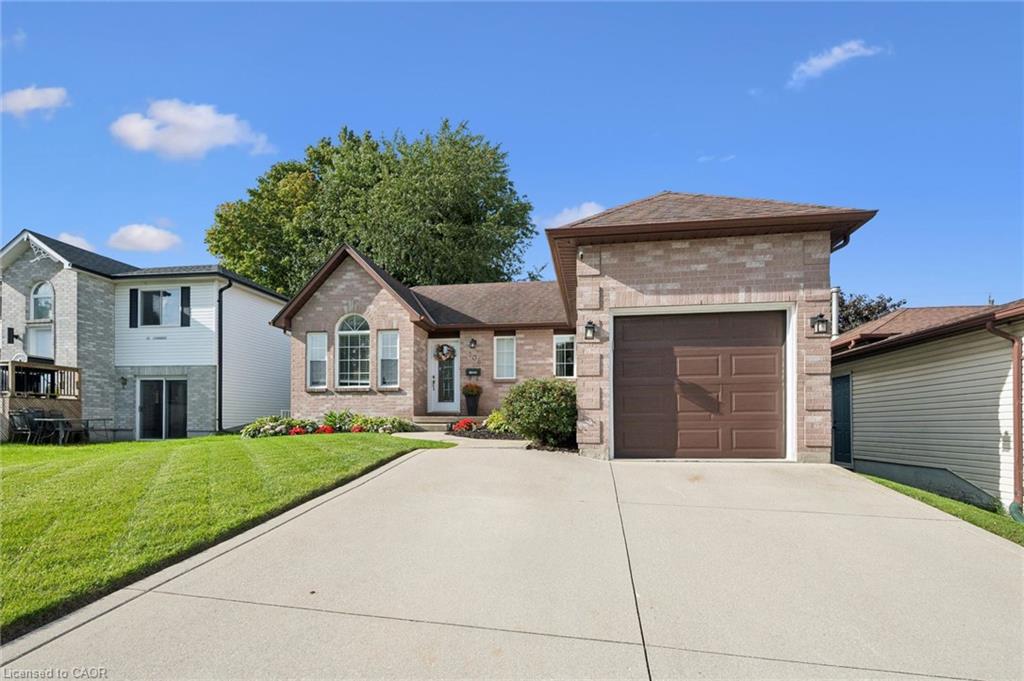 Brick exterior with an attached garage, paved driveway, and manicured front lawn