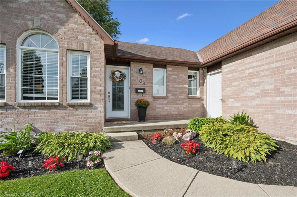 Brick exterior with an arched window, a white entry door, and a concrete walkway