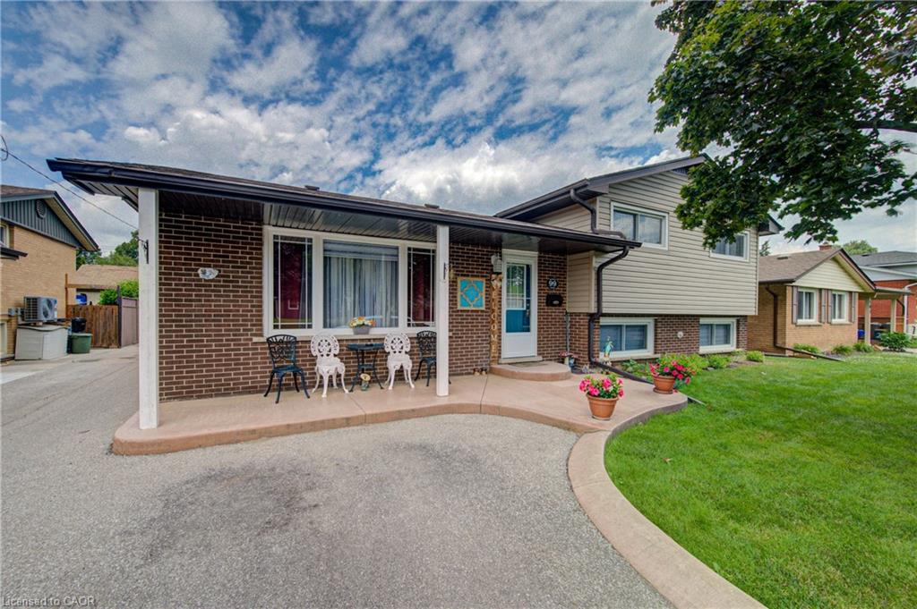 Brick and siding exterior featuring a covered front porch, concrete driveway, and expansive front lawn