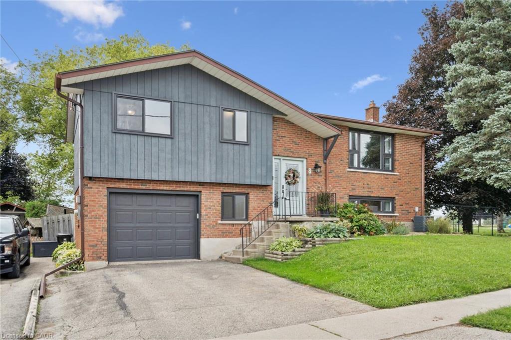 Split-level exterior featuring brick and vertical siding, attached garage, and a concrete driveway