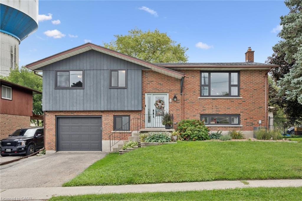 Brick and siding exterior with an attached garage, paved driveway, and mature landscaping