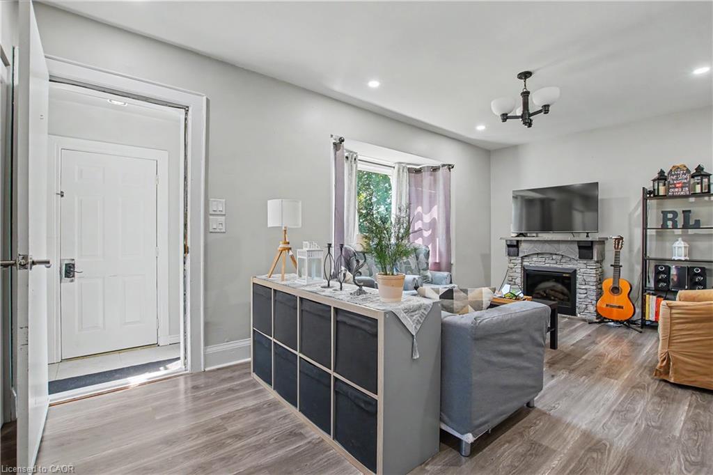 Wood-finish flooring, recessed lighting, and a stone-clad fireplace with a mantel