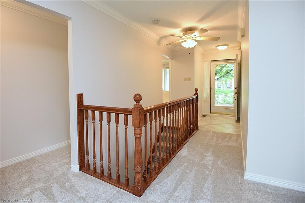 Upper-level hallway featuring light-toned carpeting, white baseboards, and crown molding