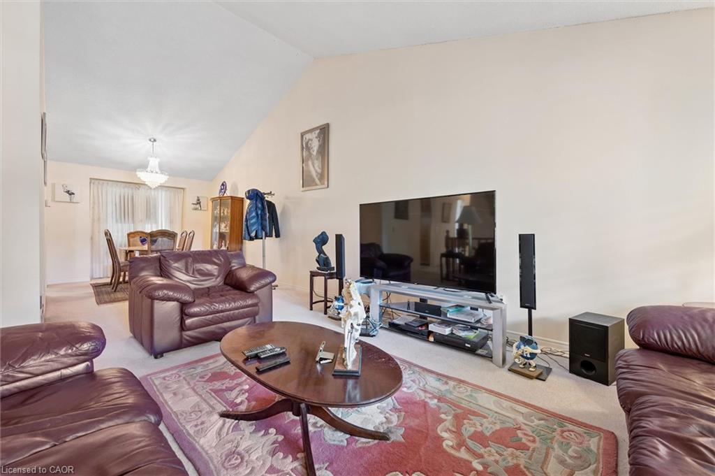 Vaulted ceiling in the living area featuring neutral wall tones and carpet flooring