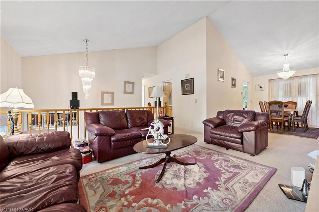 Vaulted ceilings define this living area, featuring a tiered chandelier and light-colored carpeting
