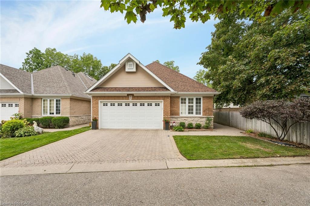 Brick exterior with stone accents, a two-car garage, and a paver driveway