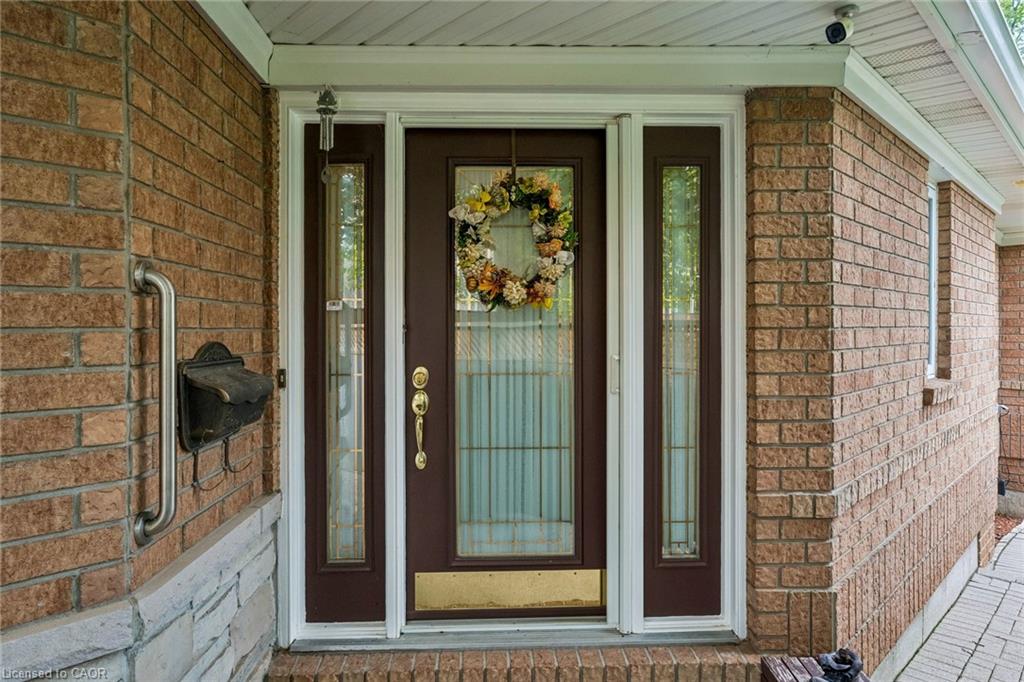 Brick exterior featuring a brown door with glass sidelights, a brass kickplate, and a brass door handle