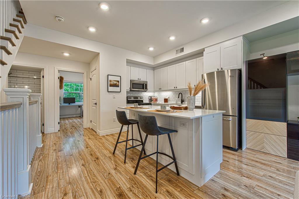 Head up a flight of stairs to the main living area with bright eat-in kitchen with gleaming hardwood flooring, quartz countertops and modern appliances.