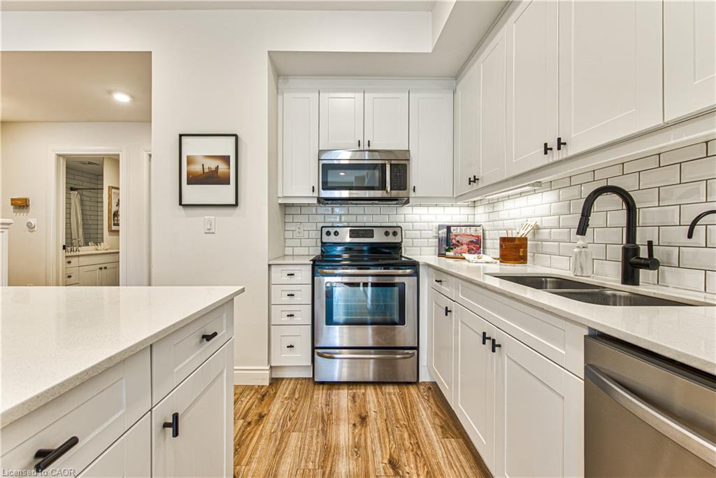 Bright eat-in kitchen with gleaming hardwood flooring, quartz countertops and modern appliances.