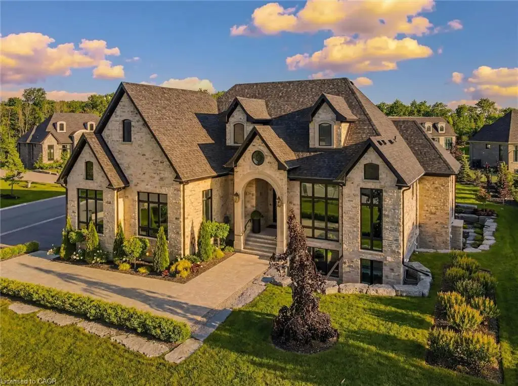 French country inspired facade with stone siding, a front lawn, and roof with shingles