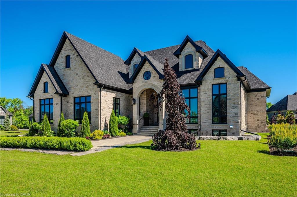 French country inspired facade featuring a front yard, brick siding, and roof with shingles