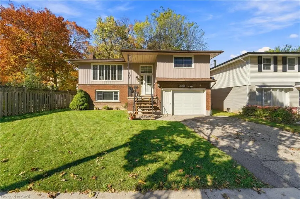 Split-level exterior featuring a brick and vinyl siding facade, an attached one-car garage, an integrated front porch with wrought-iron railing, and an expansive front lawn