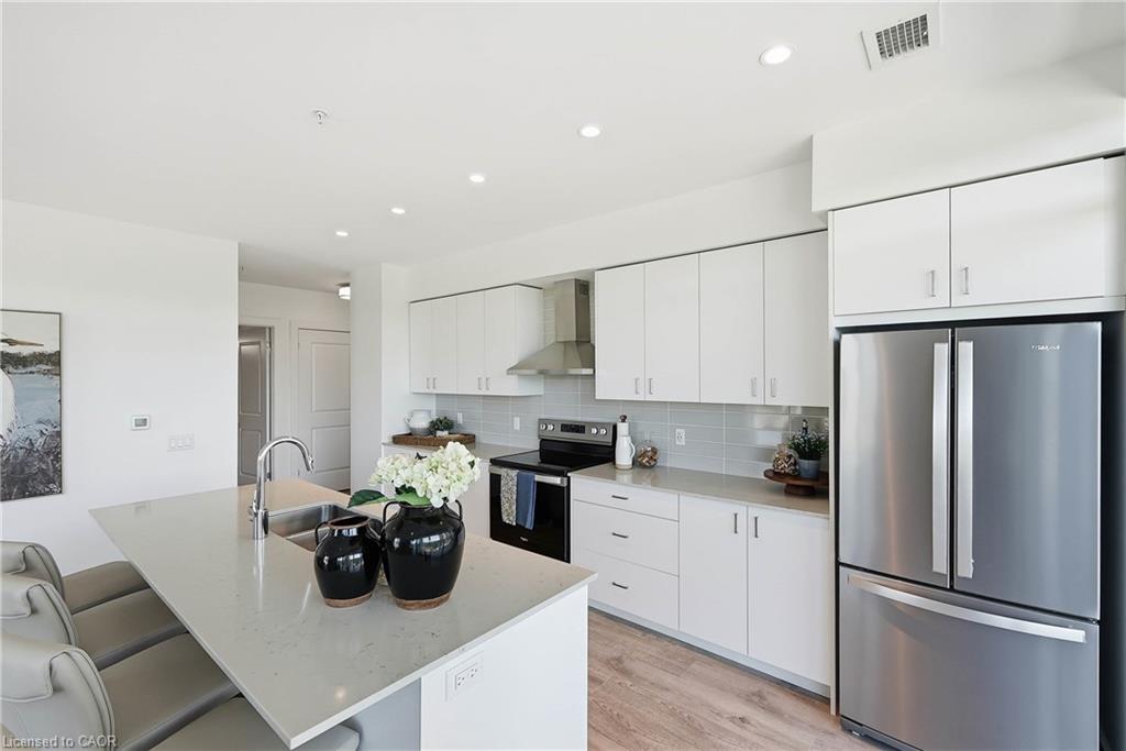 Modern kitchen featuring light wood-finish flooring, white cabinetry, light countertops, and stainless steel appliances