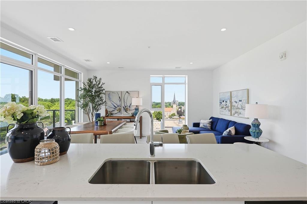 Modern kitchen featuring a stainless steel dual-basin sink with contemporary faucet, light-filled countertop with integrated workspace, recessed ceiling lighting, and expansive windows framing natural landscape views