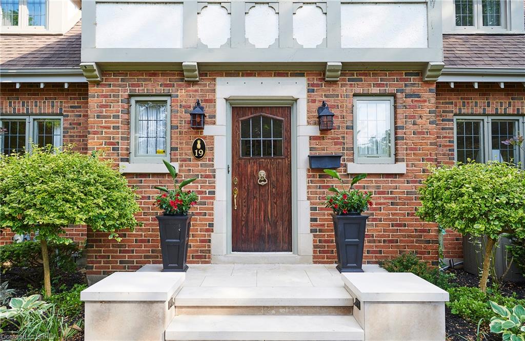 Brick facade with stone accents, wood entry door with glass panels, cast iron sconces, and a stone-clad porch