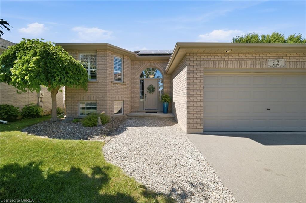 Brick exterior featuring an arched entryway, attached garage, and gravel pathway leading to the front door