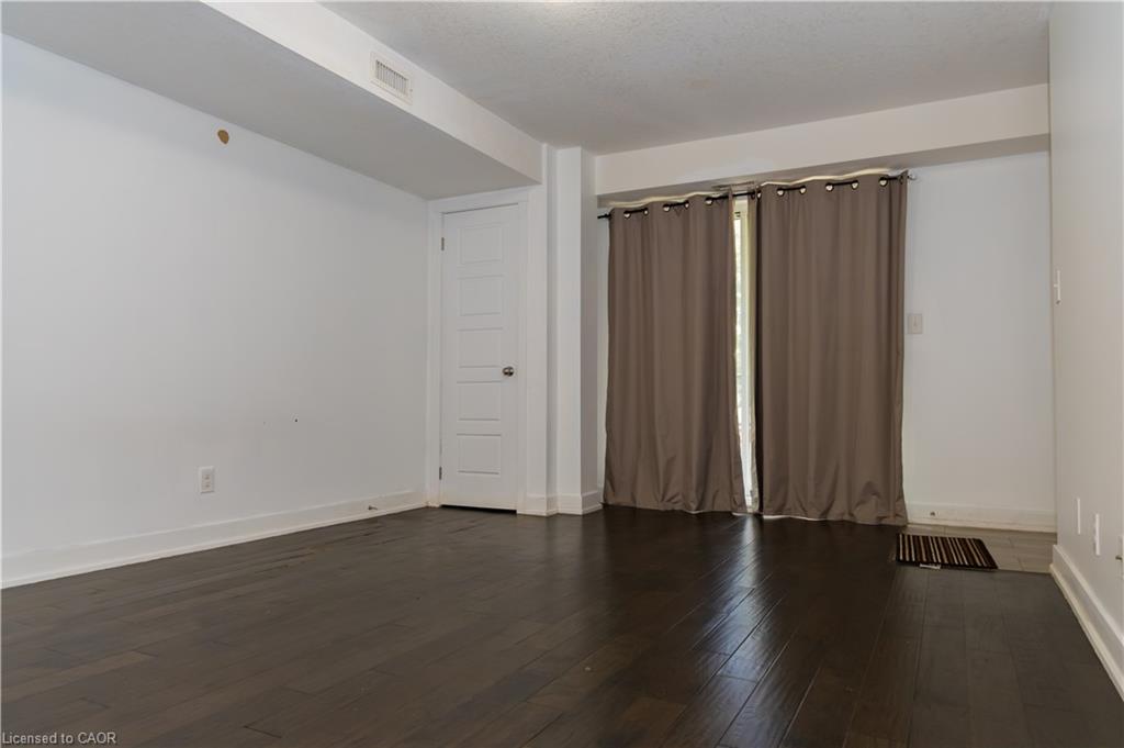 Room featuring dark wood-finish flooring, white walls, and a white five-panel interior door