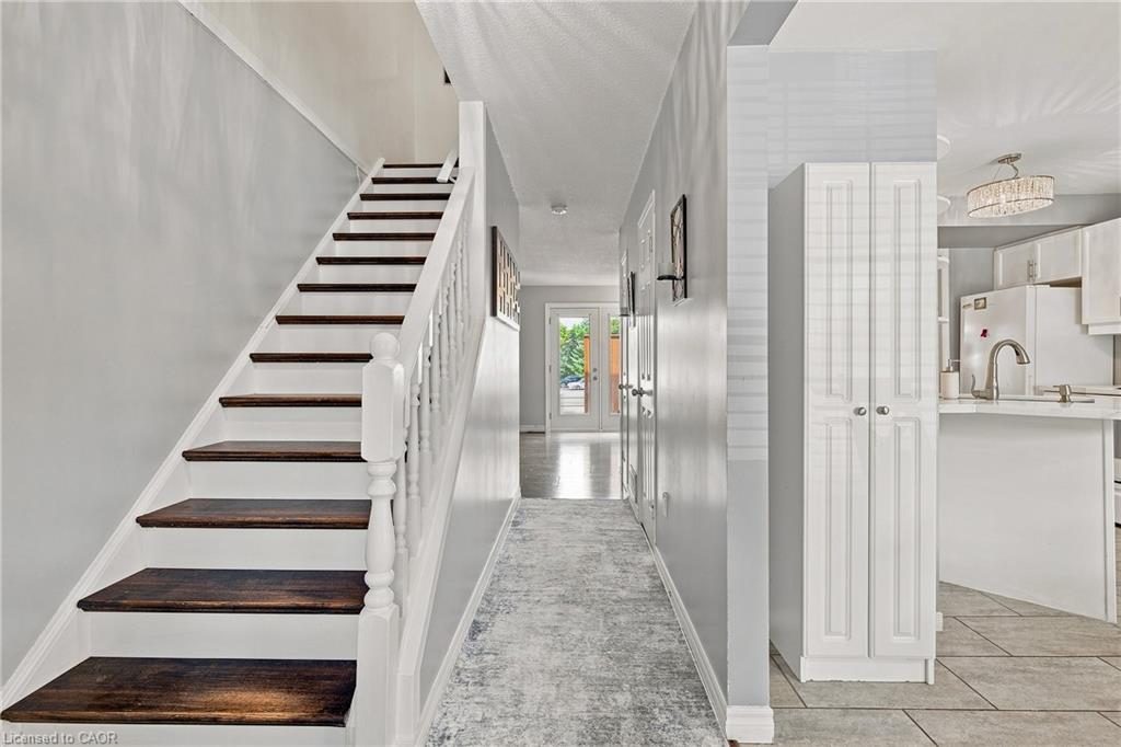 Staircase with dark wood treads and white risers, white balusters, light gray wall finishes, recessed lighting, and built-in white cabinetry