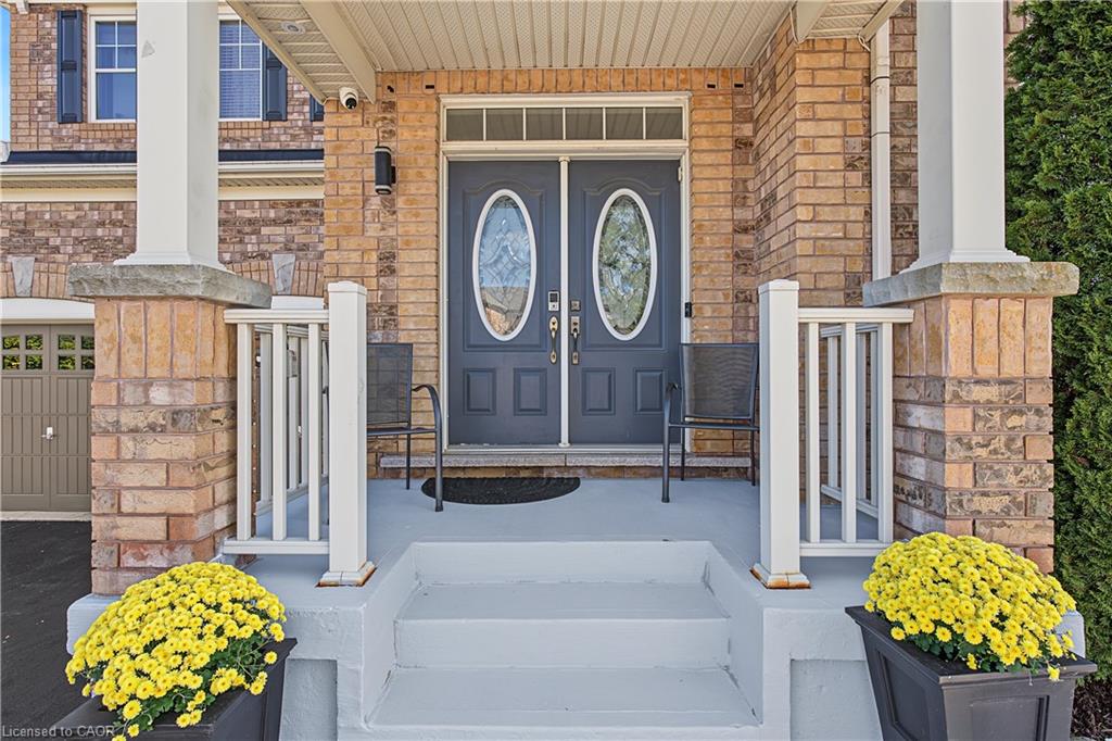Brick facade featuring a covered porch, dual entry doors with decorative oval glass inserts, and white columns with stone bases