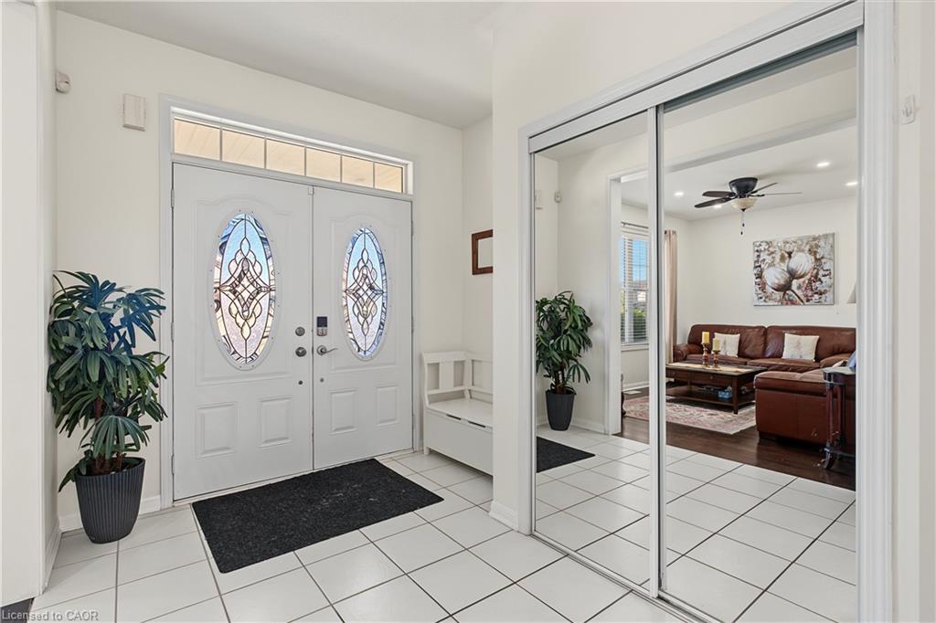 Entryway featuring white double doors with decorative glass inserts, a transom window, and white square floor tiles