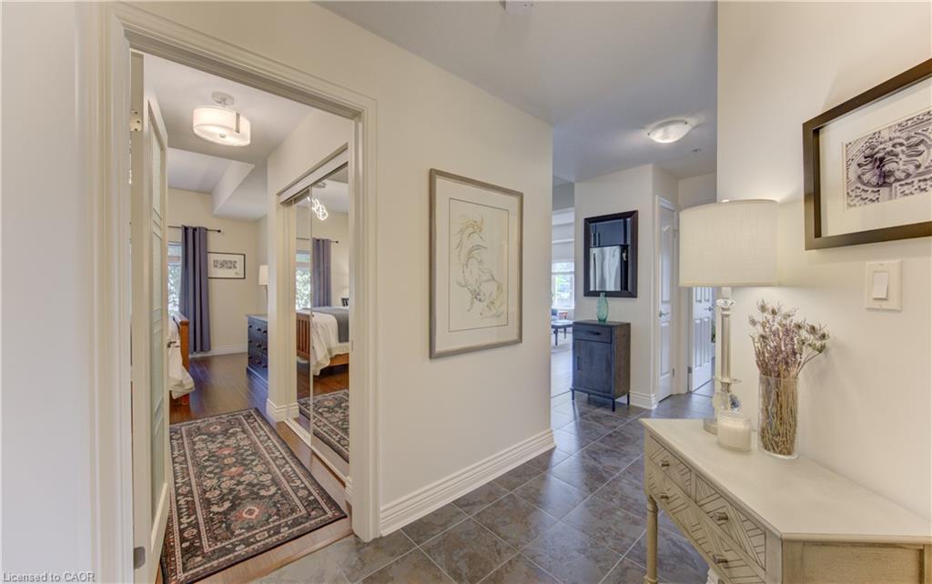 Hallway featuring dark tile flooring, white baseboards, and a doorway opening to a room with wood-finish flooring and mirrored closet doors