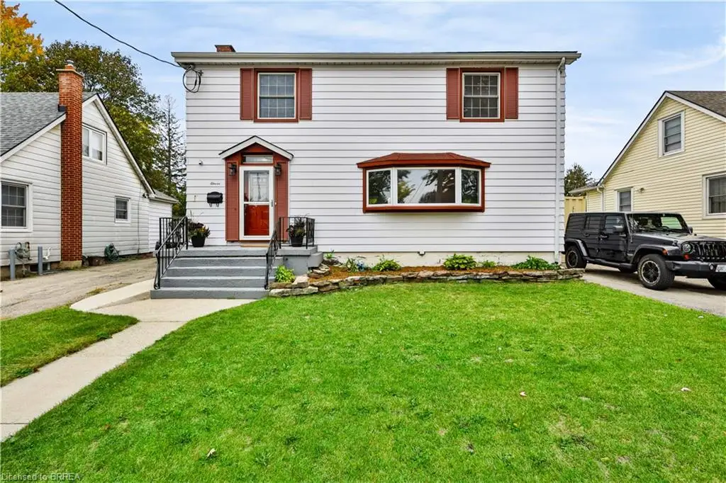 White siding exterior with a red front door, bay window, and dark shutters