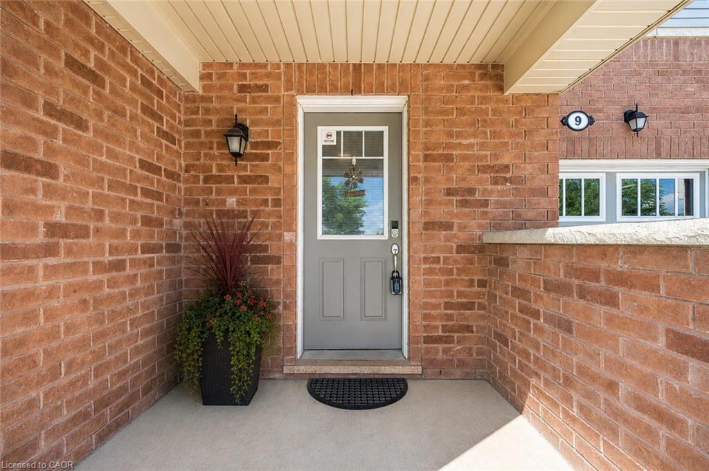 Brick exterior featuring a recessed entrance, a gray door with an upper glass panel, a concrete porch, and exterior sconce lighting