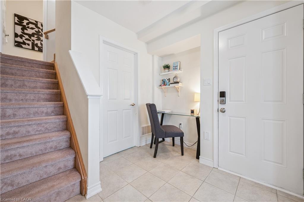 Entryway featuring a white panel door with smart lock, tile flooring, and a built-in alcove with floating shelves