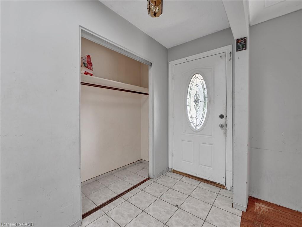 Entryway with a tiled floor, white paneled door featuring an oval decorative glass insert, and an overhead light fixture