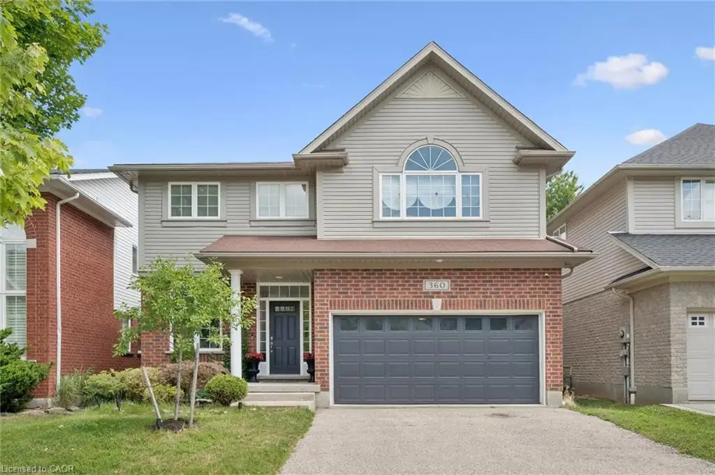 Two-story residence featuring brick and siding exterior, an integrated garage with a dark gray door, a paved driveway, and a front entrance with a dark door and side windows