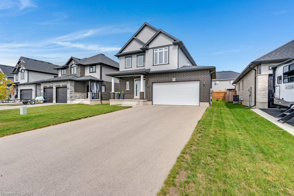 Modern two-story residence featuring a two-car garage, partial brick and siding exterior, front porch with columns, and a paved driveway