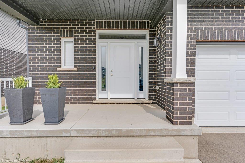 Front entry with gray brick facade, white panel door with sidelights, concrete porch, and integrated garage door