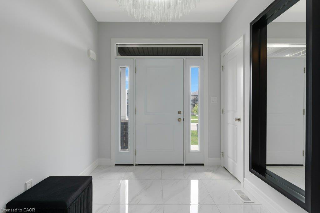 White front door with transom and sidelight windows, polished tile flooring, and a contemporary light fixture