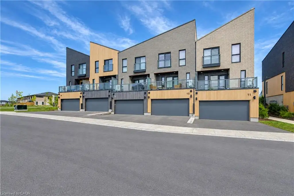 Modern townhouse exterior featuring brick and wood-finish siding, multiple balconies with glass railings, and individual garage doors