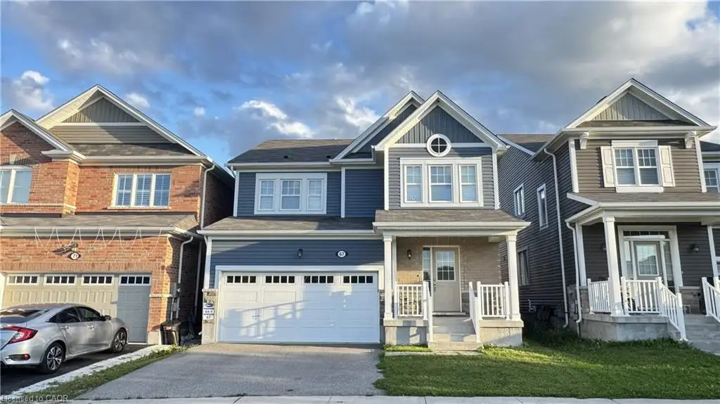 Gable roofline, prominent front porch, attached garage, stone and siding exterior finishes, and a manicured front lawn