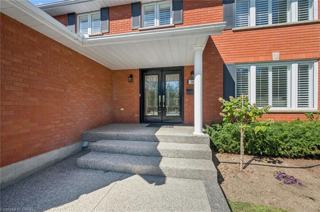 Brick exterior with a covered entry, double glass-paneled entry doors, and a concrete walkway