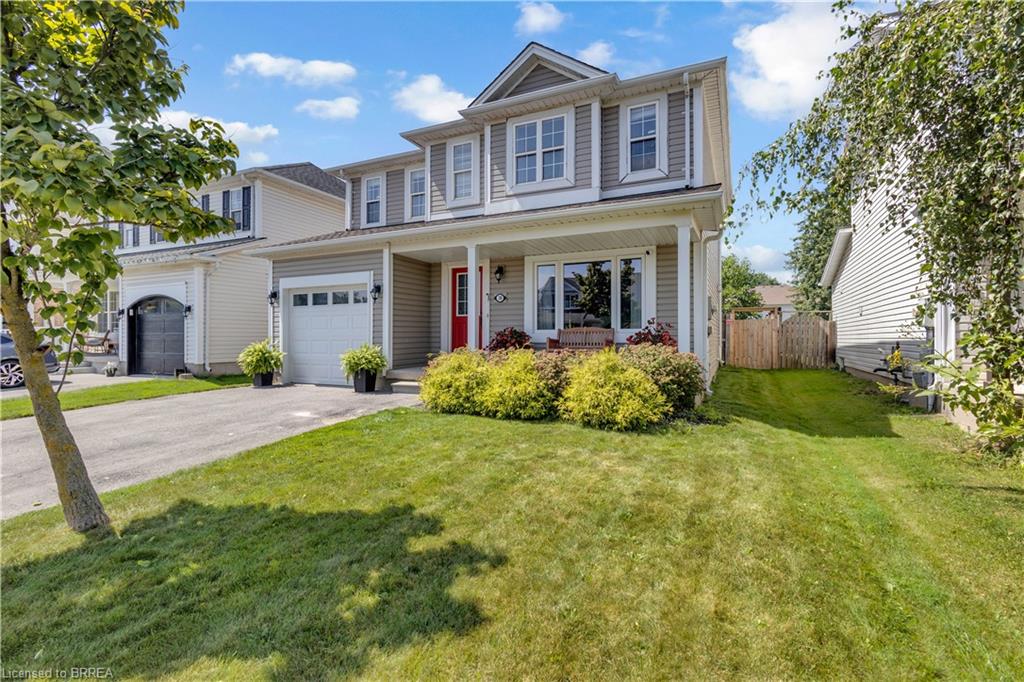 Two-story residential structure featuring a covered front porch, an attached garage, and a paved driveway