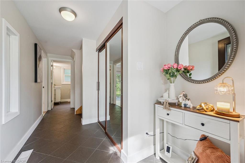 Hallway featuring dark tile flooring, a flush-mount ceiling light, and mirrored closet doors