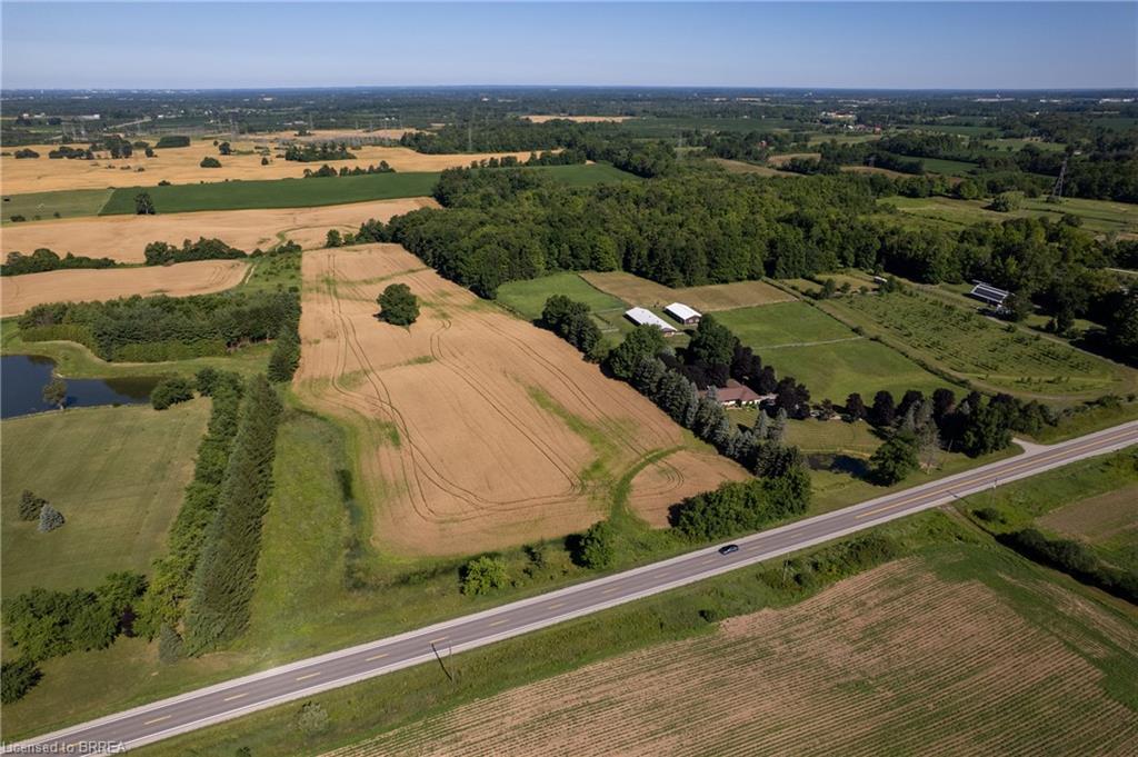 Expansive rural property featuring cultivated fields, mature tree lines, a private pond, and multiple outbuildings