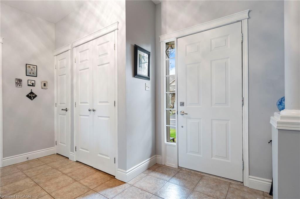 Entryway with decorative sidelight, tile flooring, and closet storage