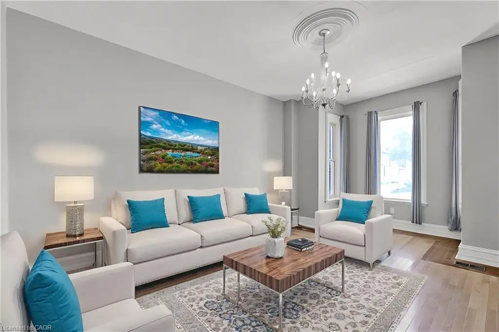 Living area featuring wood-finish flooring, ceiling medallion, multi-light crystal chandelier, and tall windows