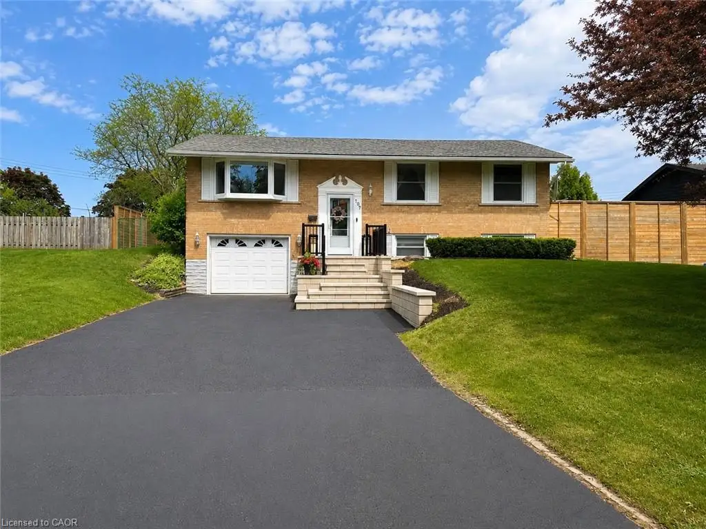 Split-level residence featuring a brick facade, attached garage, and asphalt driveway