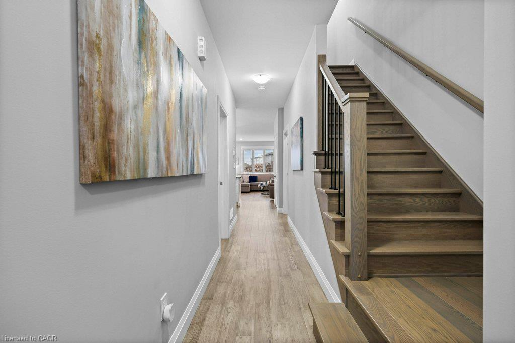 Wood-finish flooring throughout, solid wood staircase with black iron spindles, wood handrail