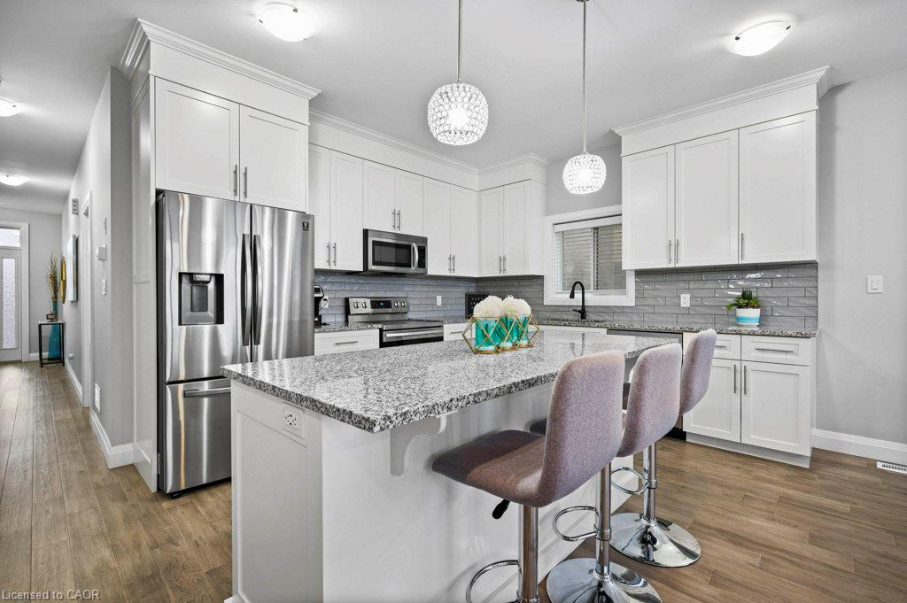 Kitchen featuring white shaker cabinetry, stainless steel appliances, a grey subway tile backsplash, granite countertops, and wood-finish flooring