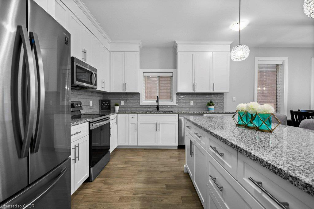 Kitchen featuring white cabinetry, stainless steel appliances, grey tile backsplash, granite countertops, and wood-finish flooring