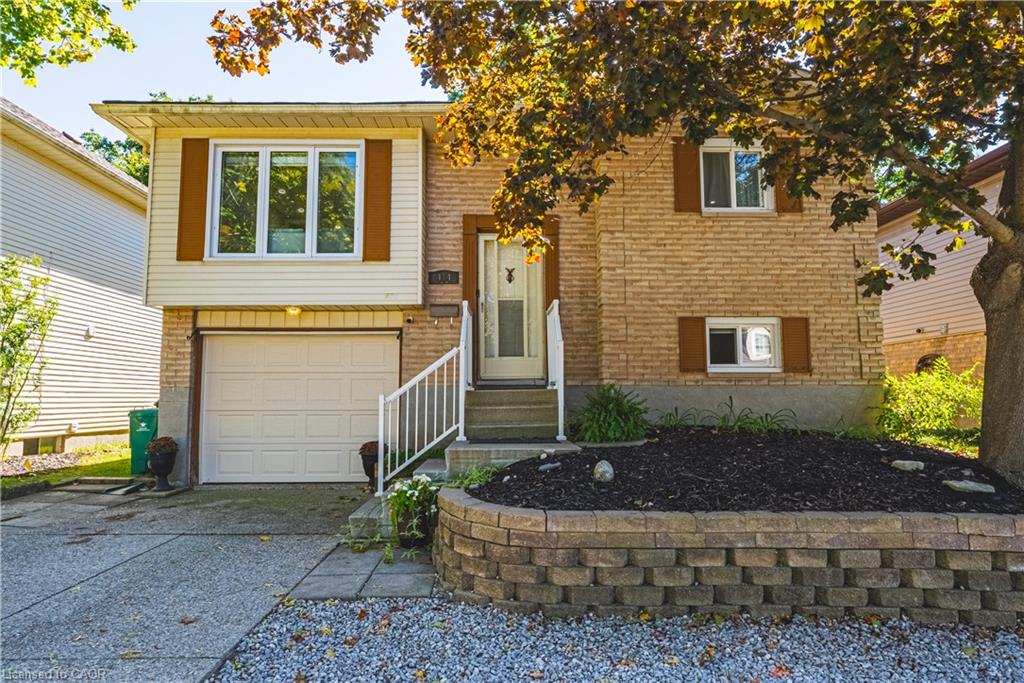 Brick and siding exterior with a dedicated garage, concrete driveway, and front landscaping featuring a stone retaining wall