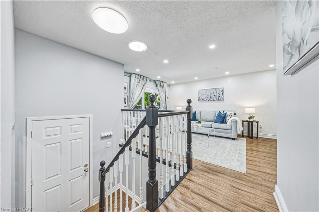 Wood-finish flooring throughout, recessed ceiling lighting, and a white paneled door