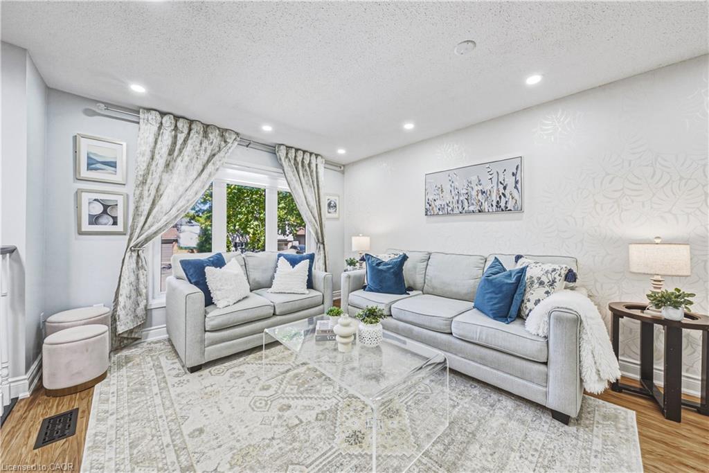 Recessed lighting illuminates the living area with wood-finish flooring and a decorative accent wall