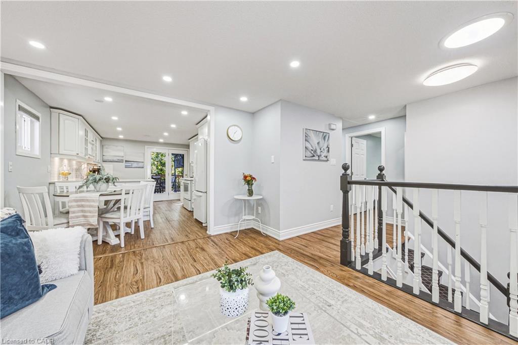 Wood-finish flooring throughout, with recessed lighting and a staircase featuring a black handrail and white spindles
