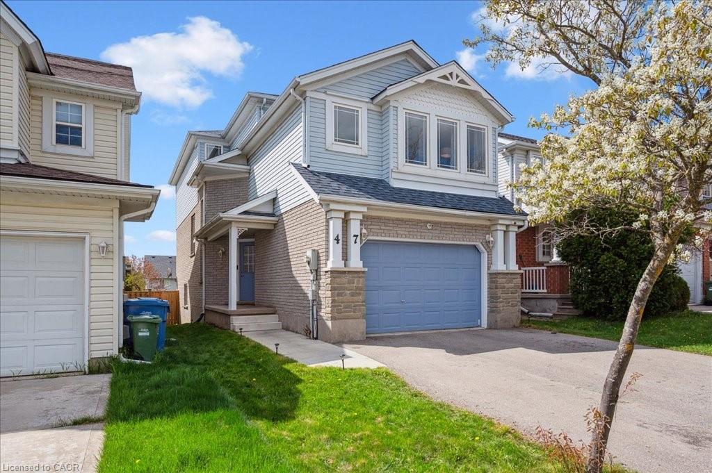 View of front of property with an attached garage, brick siding, asphalt driveway, and a front yard